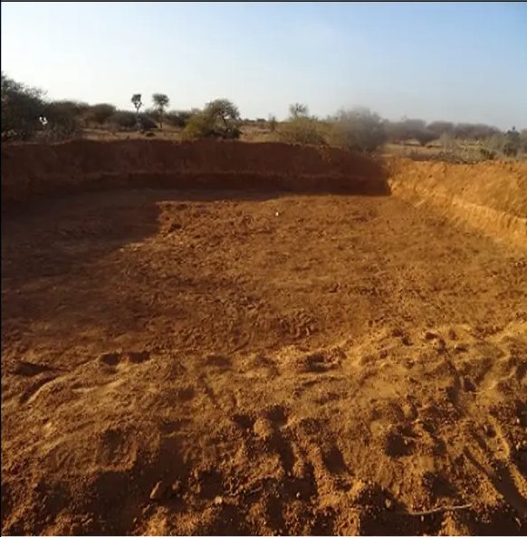 Squared-off catchment cut into red soil with clean walls and a graded floor
