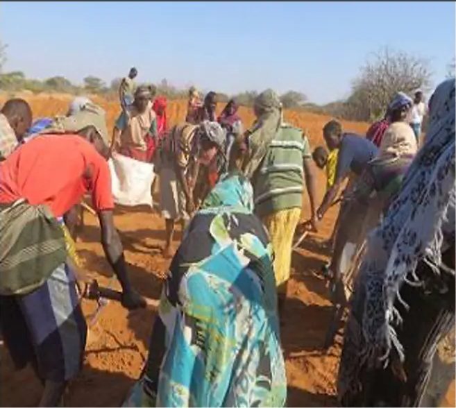 Crowd of villagers carrying sacks of spoil out of the widening excavation