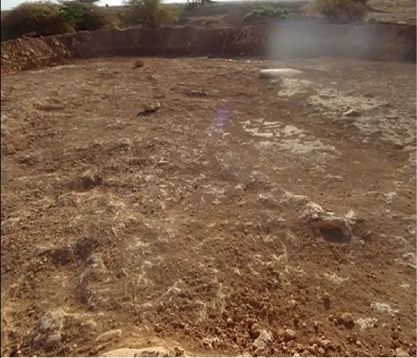 Deepened basin with a steep excavated rim curving around bare ground