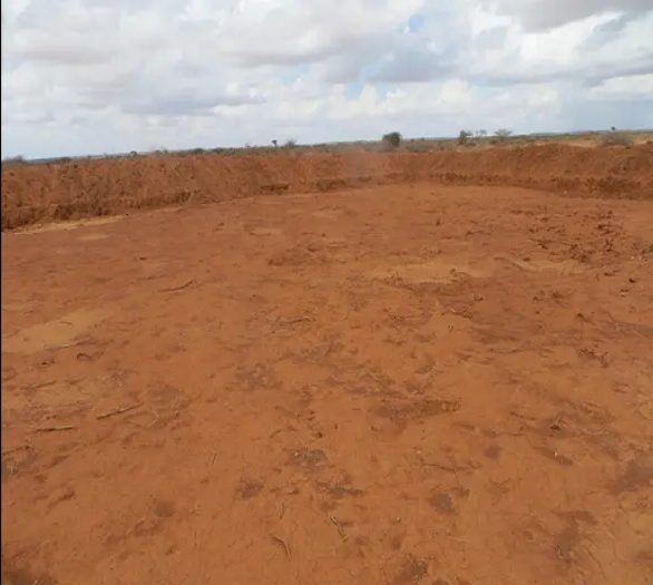 Broad excavated bowl of red earth with a raised perimeter bank
